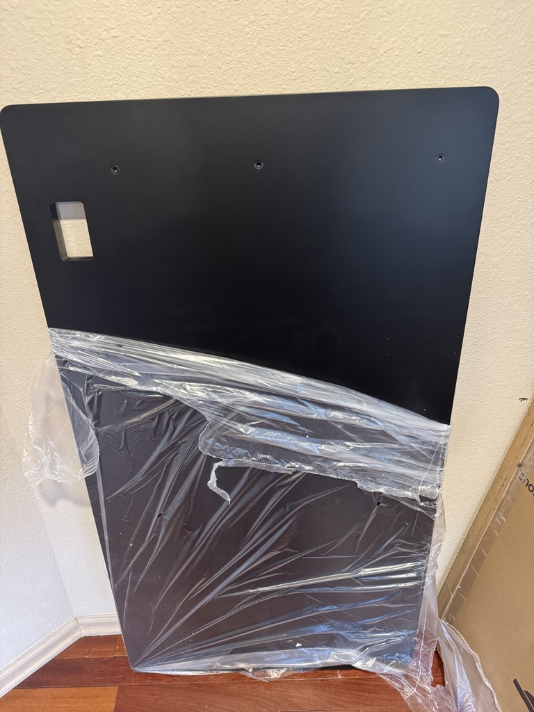 Black Autonomous Desk Pro tabletop unwrapped, showing screw holes and cutout for glass controls